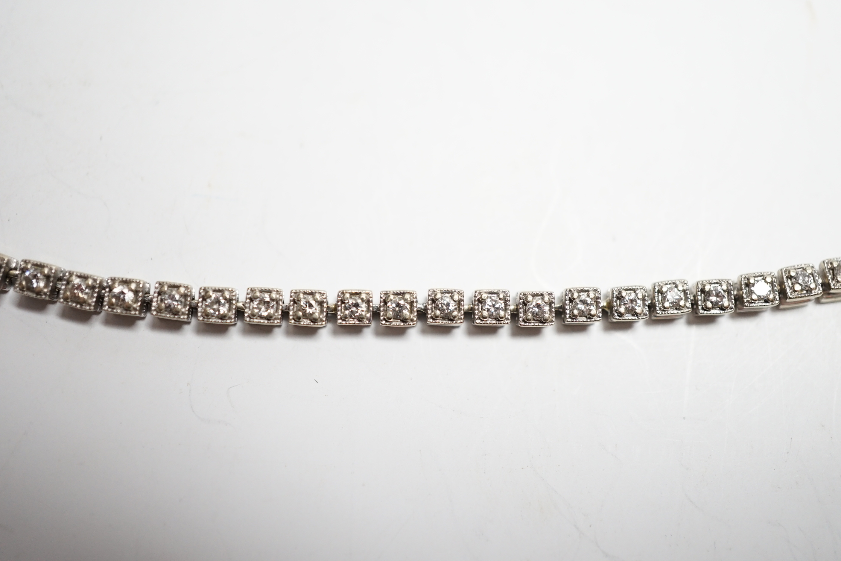 A 750 white metal and diamond line bracelet, set with sixty small stones, 20.8cm, gross weight 12 grams.
